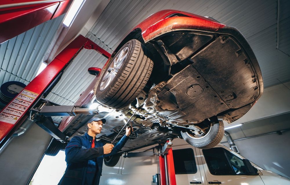 A Man is Working on a Car on a Lift in a Garage — East Coast Mechanic in Macksville, NSW