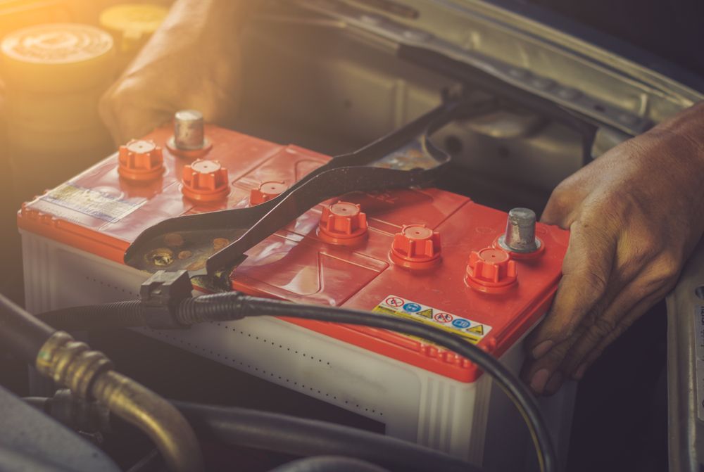 A Person is Plugging a Red Battery Into a Car — East Coast Mechanic in Nambucca Heads, NSW