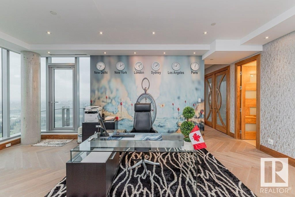 Office with large desk, world time clocks on wall, city view.