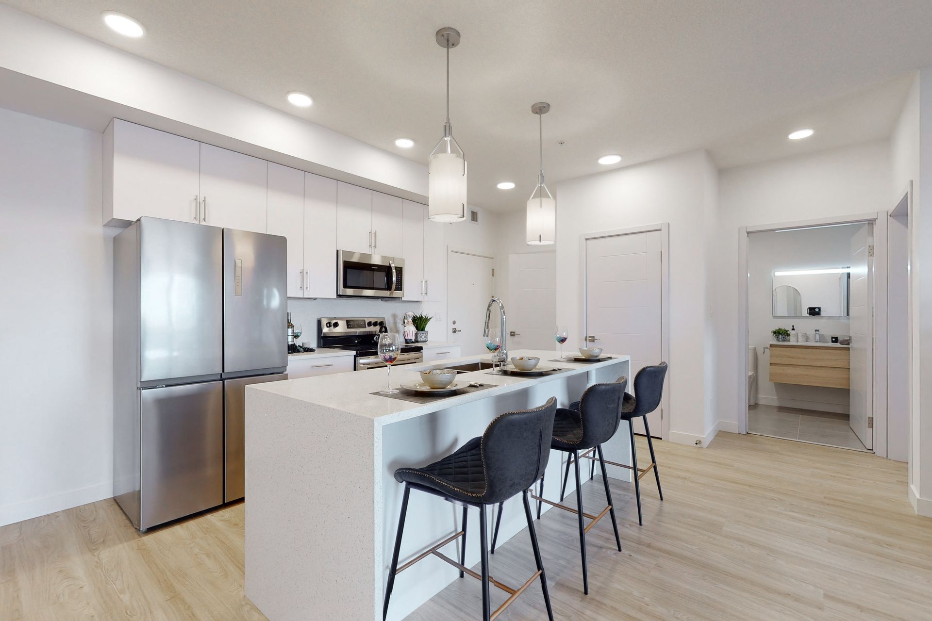 A kitchen with stainless steel appliances and a large island with stools.