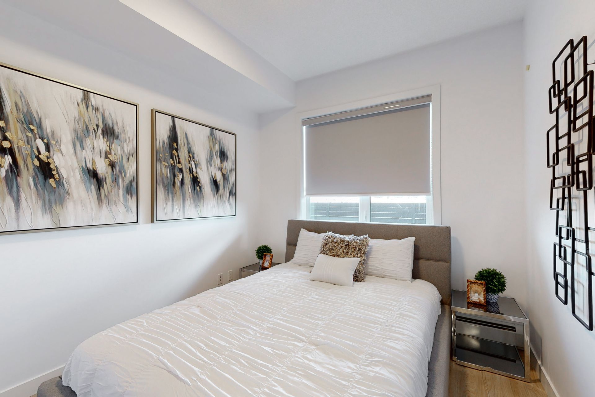 A bedroom with a bed , two nightstands , and three paintings on the wall.