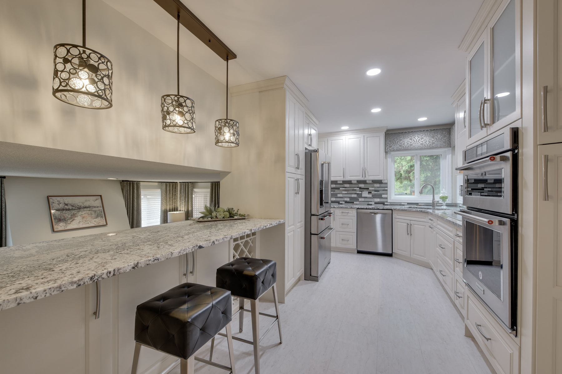 A kitchen with white cabinets , granite counter tops , and stainless steel appliances.