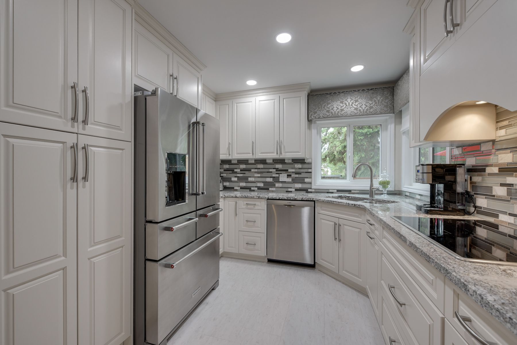 A kitchen with white cabinets , stainless steel appliances and granite counter tops.