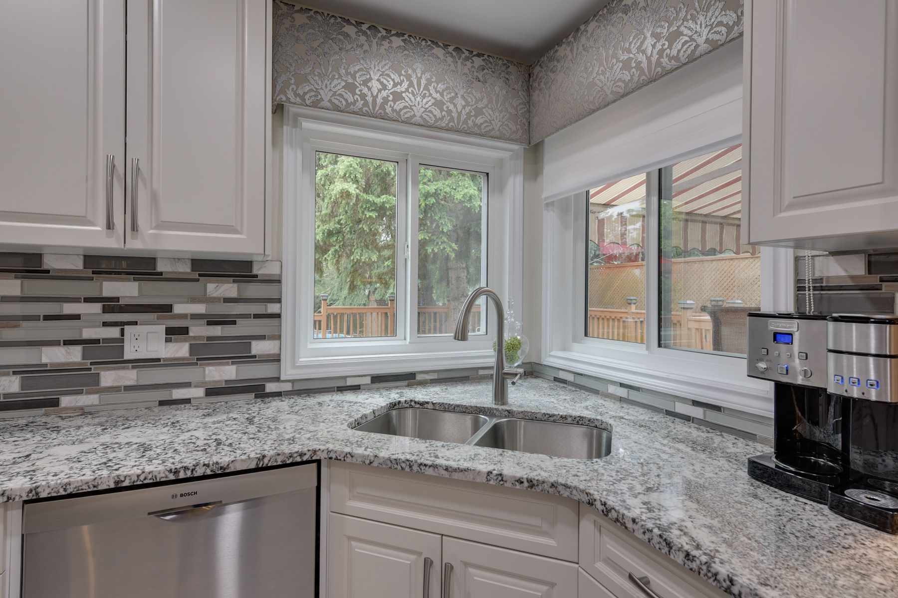A kitchen with granite counter tops , stainless steel appliances , a sink and a window.