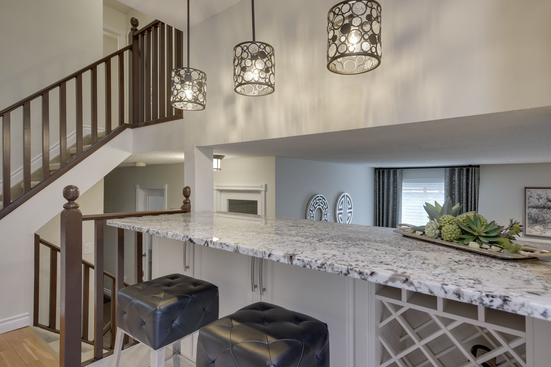 A kitchen with a bar and stairs leading up to the second floor.