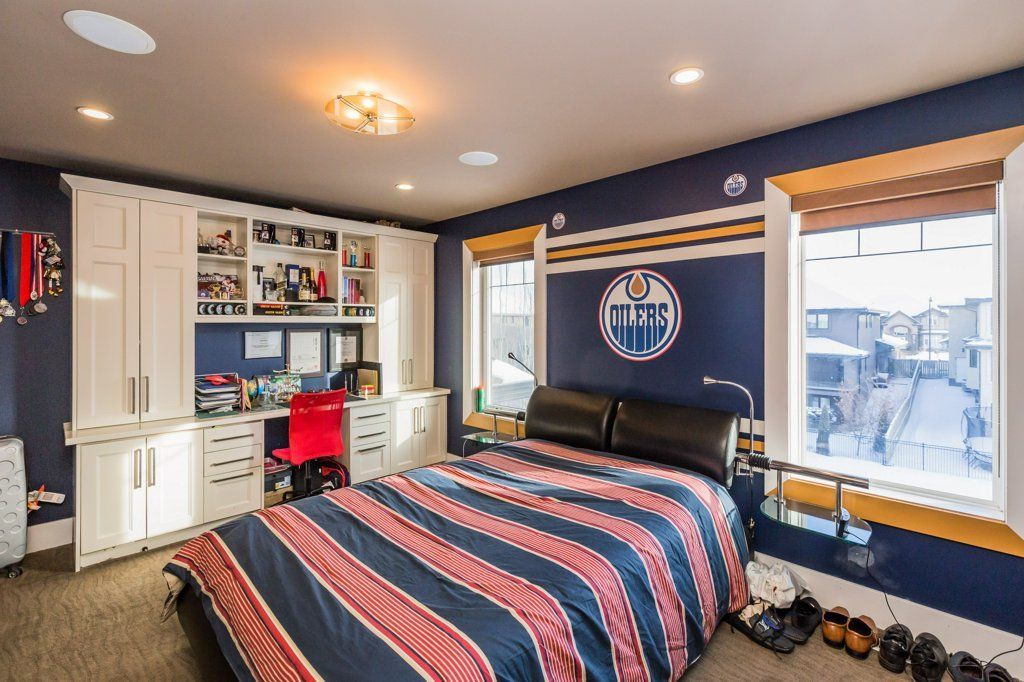 A bedroom with a bed , a desk , and a window.