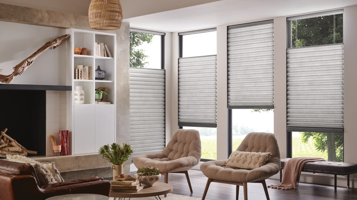 Living room with large windows, light blinds, two chairs, and a fireplace.