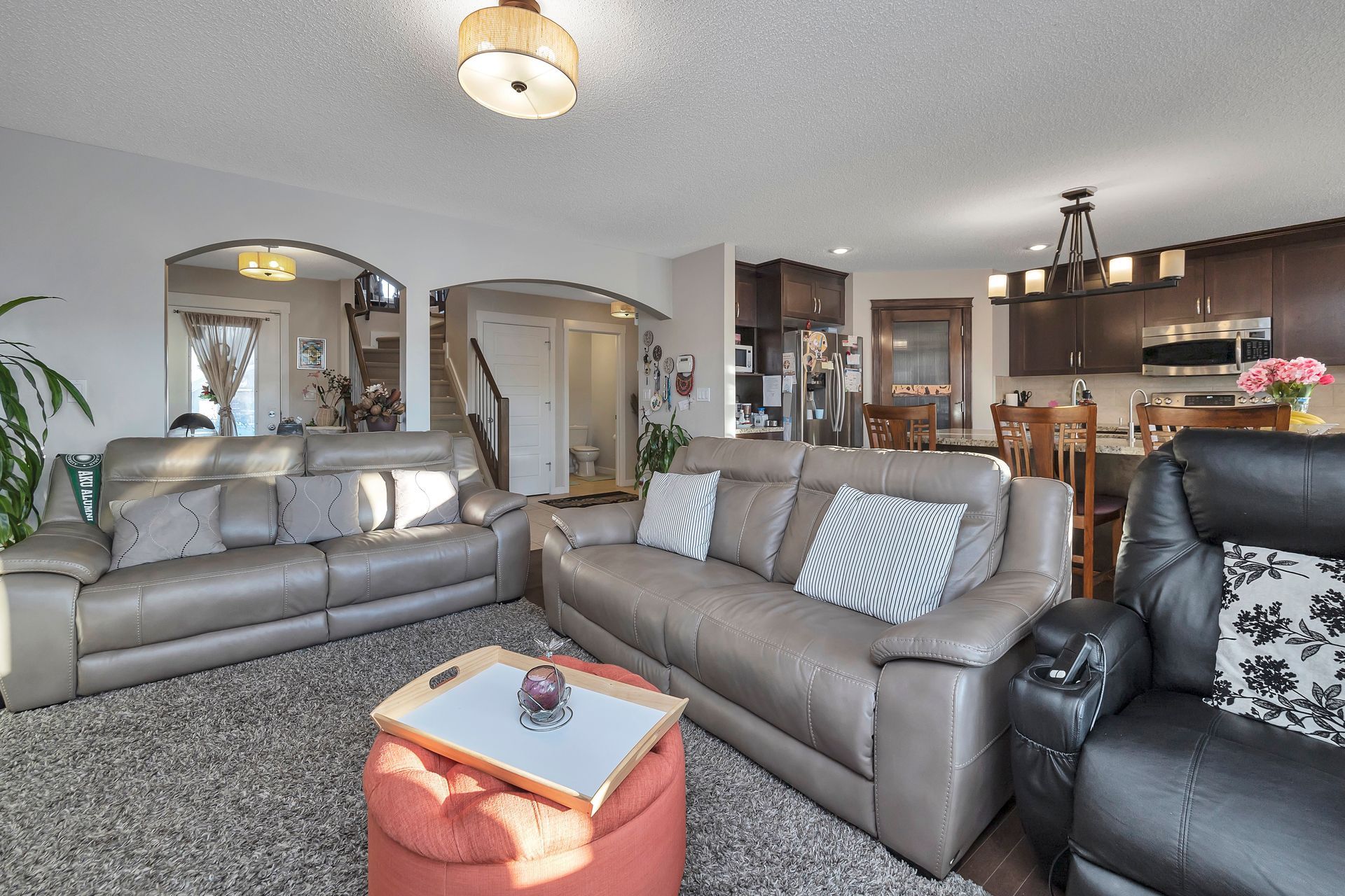 Living room with grey sofas, red ottoman, and open to kitchen/dining area.