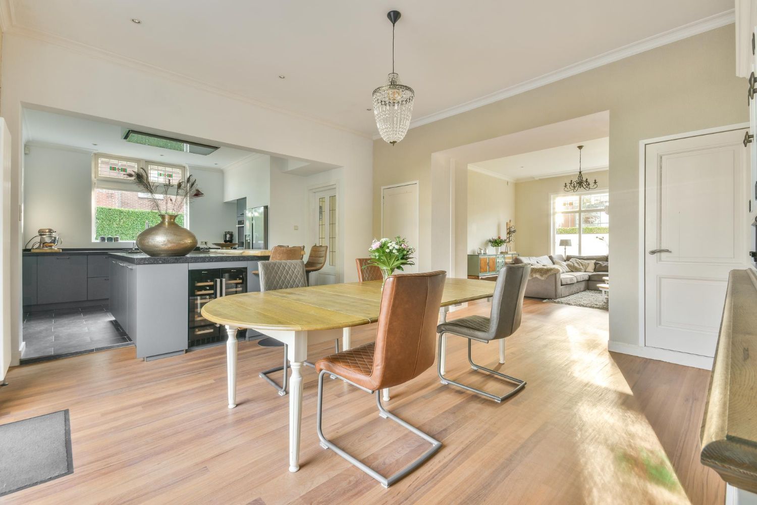 Bright dining room with wooden table, modern chairs, and open kitchen in a sunlit home