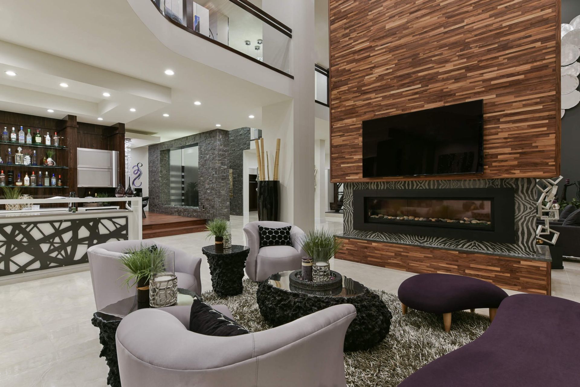 Living room with fireplace, TV, couches, bar, and a mezzanine level; modern design.