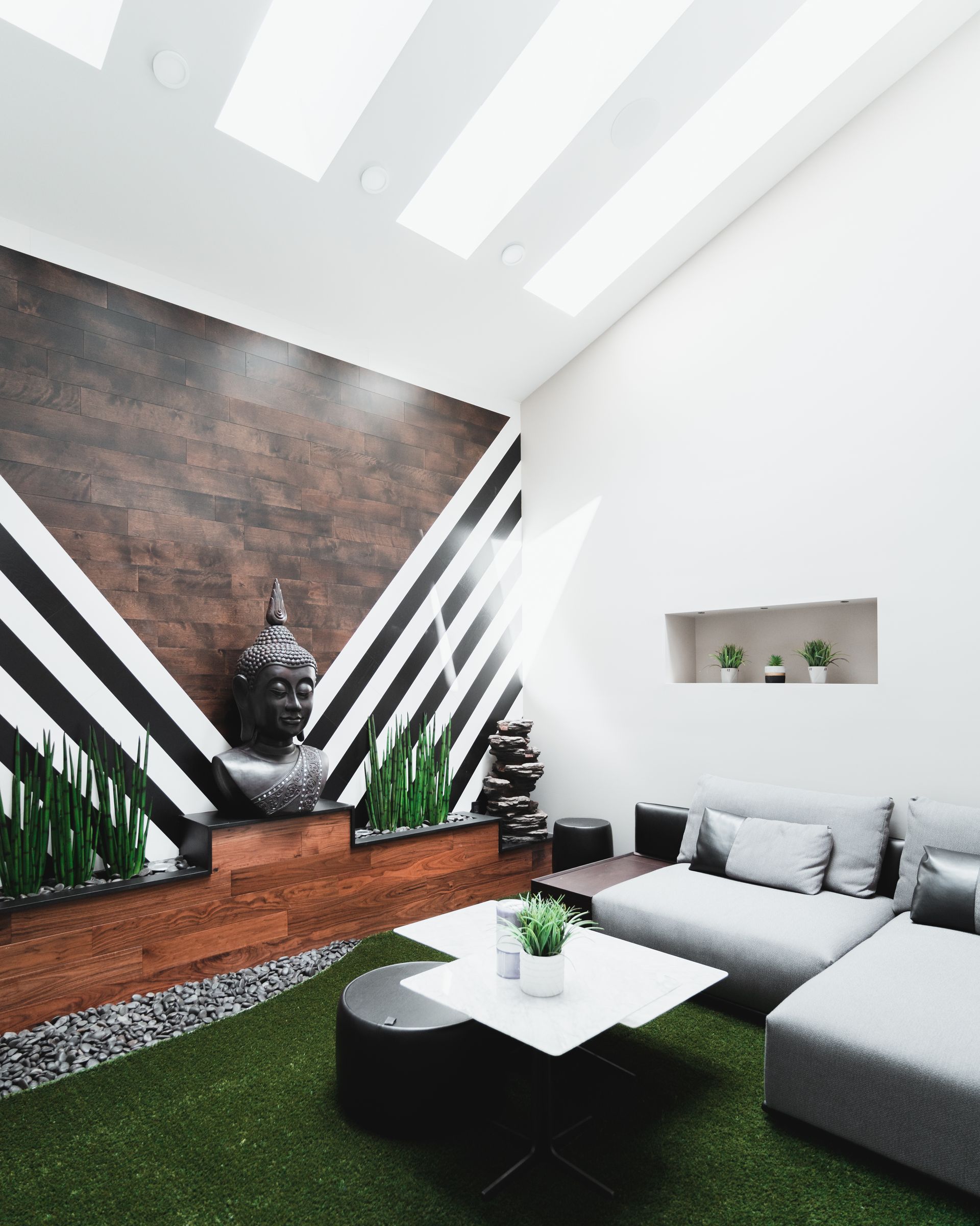 Modern living space with Buddha statue, gray sofa, and geometric accent wall.