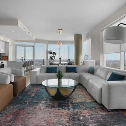 Modern living room with white sectional sofa, round coffee table, and city view through large windows