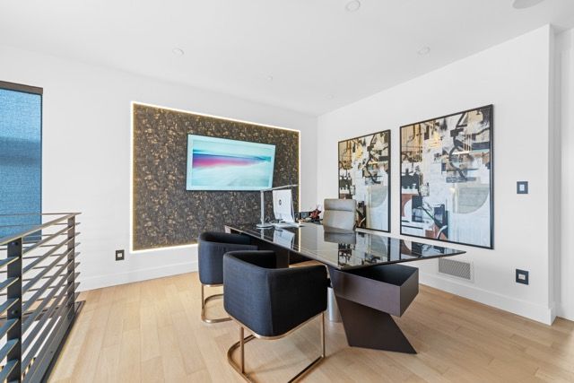 A dining room with a table and chairs and a flat screen tv on the wall.