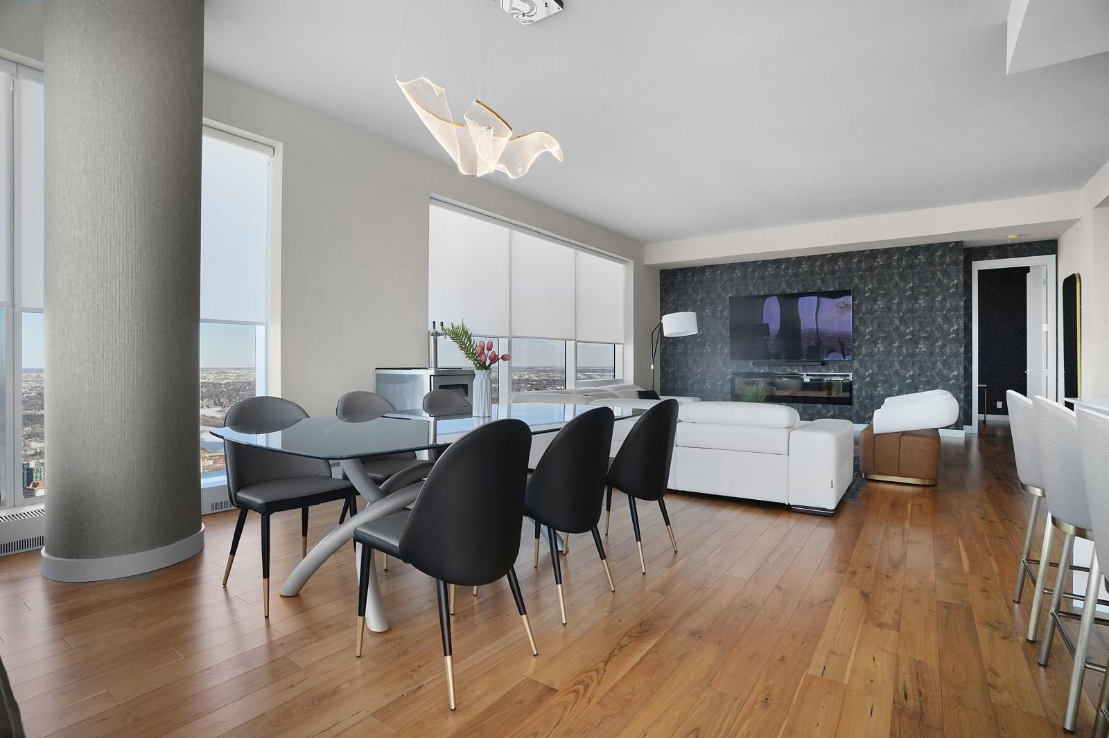Modern dining and living area with city views, hardwood floors, and black and white furniture.