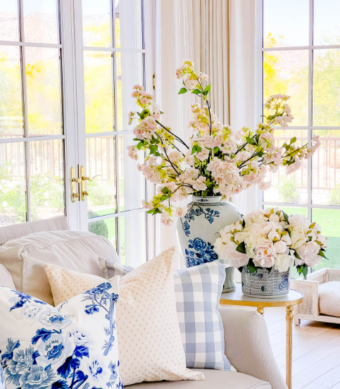 A living room with blue and white pillows and a vase of flowers