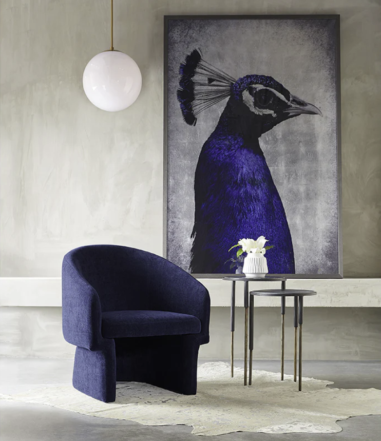 A room with a chair and a painting of a peacock on the wall