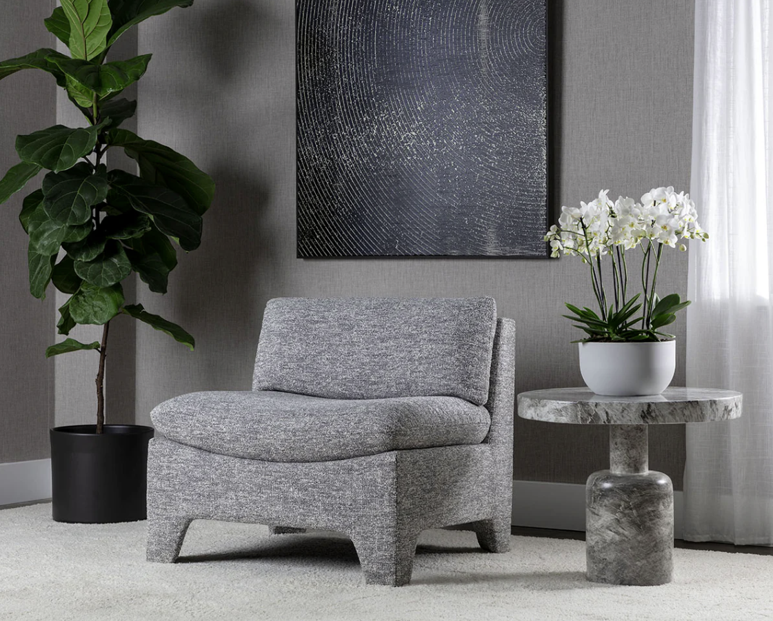 A chair is sitting next to a table with flowers on it in a living room.