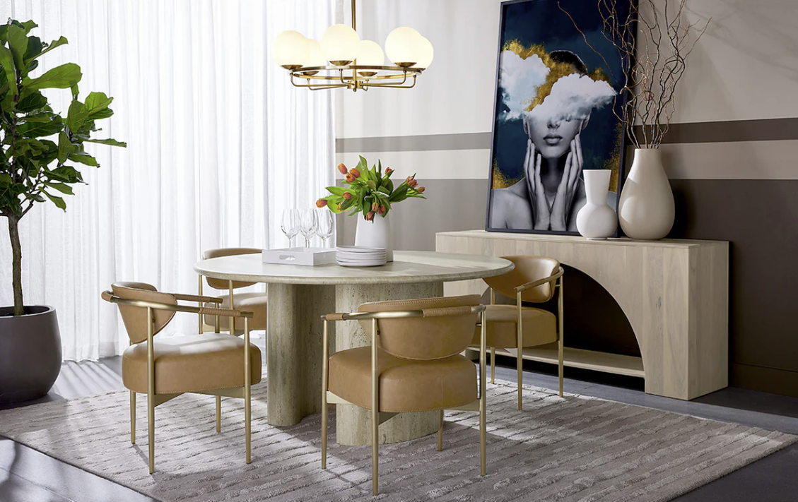 A dining room with a table and chairs and a painting on the wall.