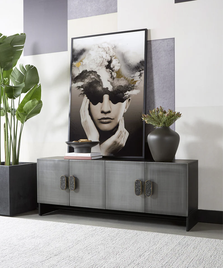 A picture of a woman 's face is hanging on a wall above a cabinet.