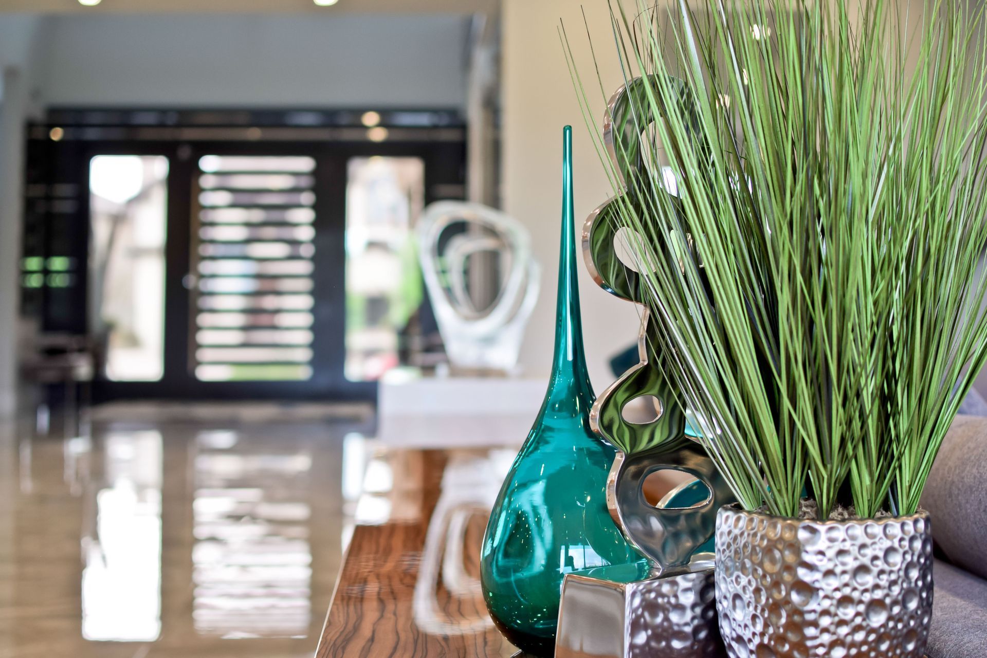 A living room with a plant and vases on a table.