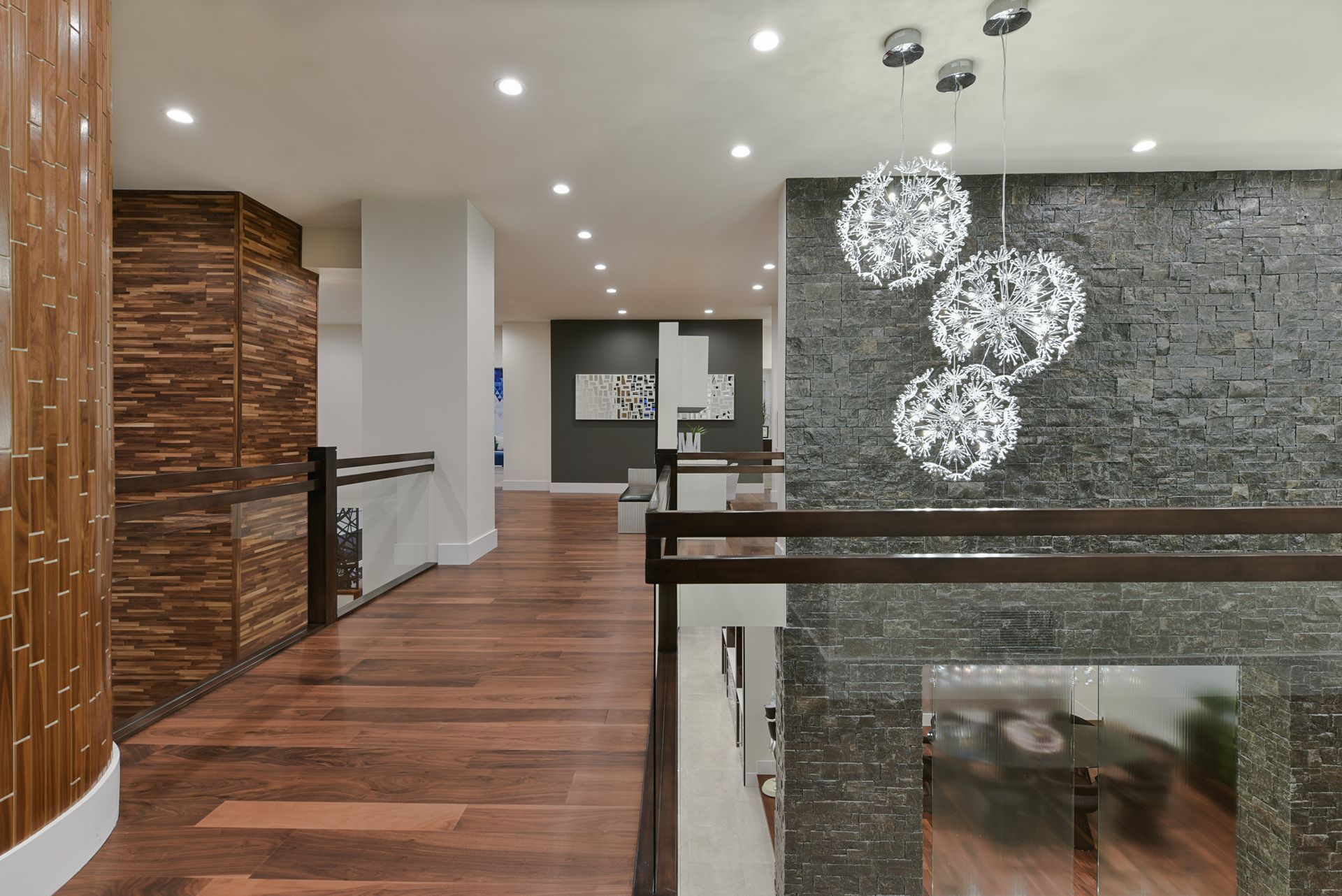 A hallway in a house with wooden floors and a chandelier hanging from the ceiling.