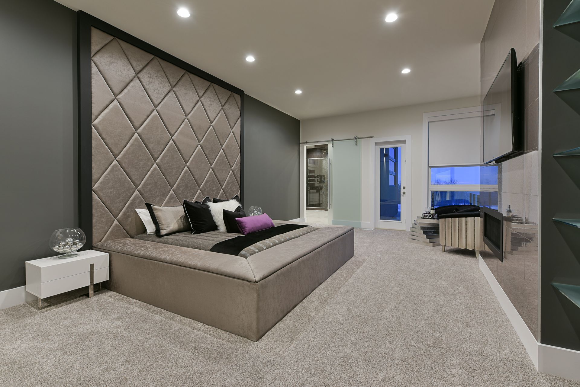 A bedroom with a large bed and a television on the wall.