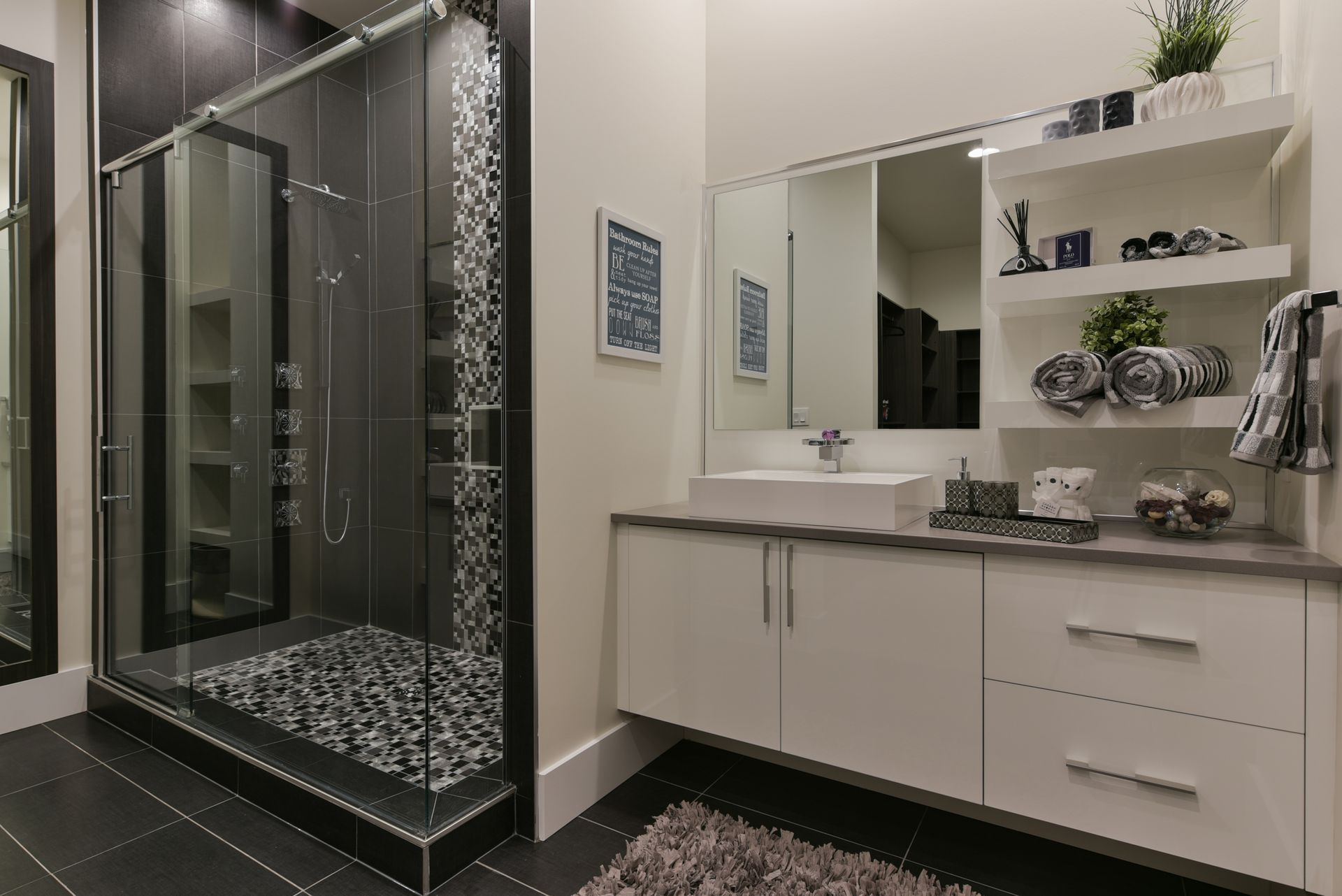A bathroom with a sink , mirror and walk in shower.