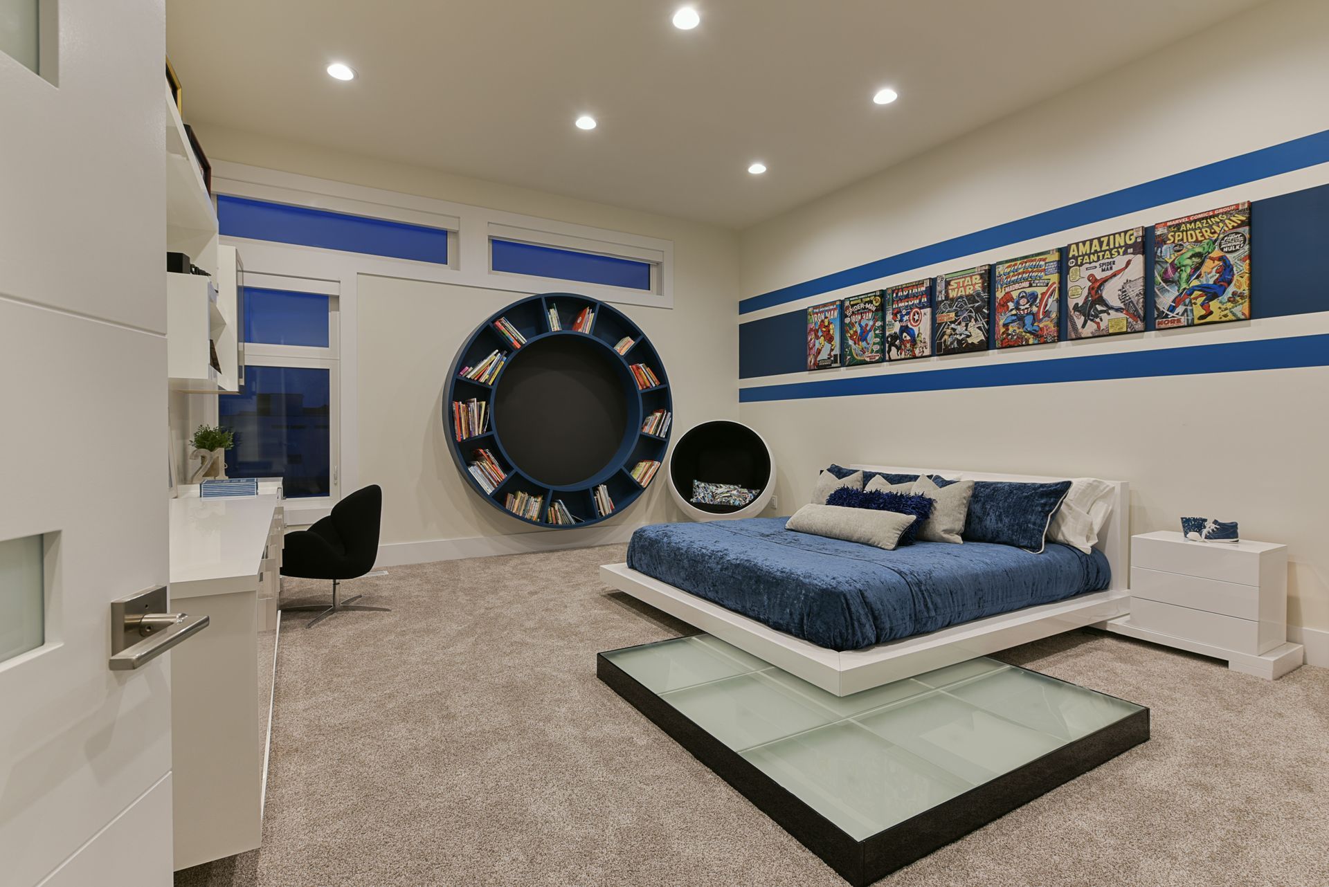 A bedroom with a bed , desk , chairs and a circular shelf on the wall.