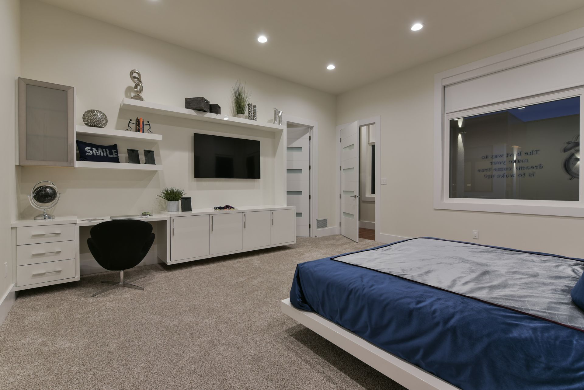 A bedroom with a bed , desk , television and window.