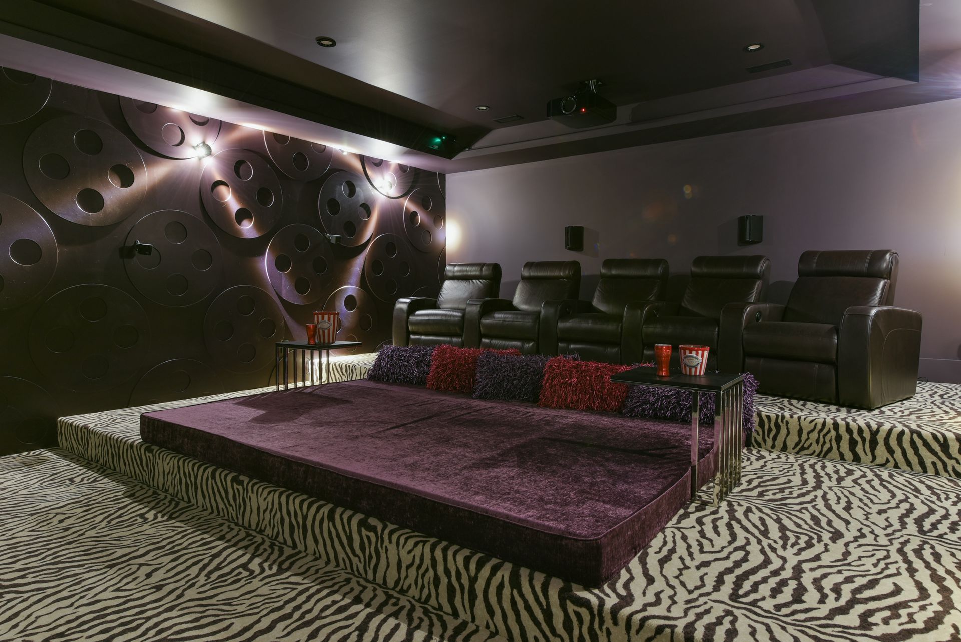 A home theater with a purple couch and black chairs