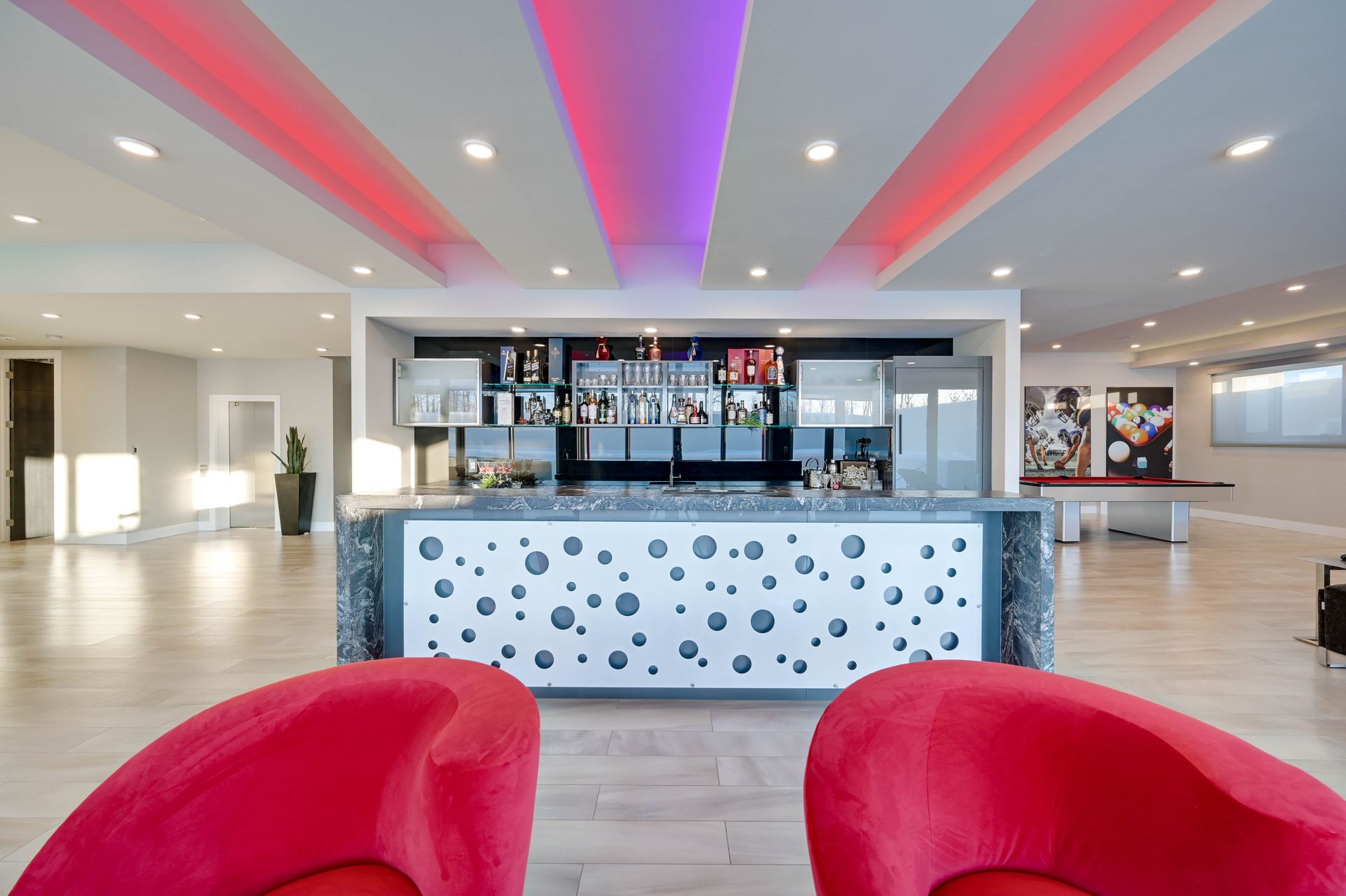 Two red chairs are sitting in front of a bar in a hotel lobby.