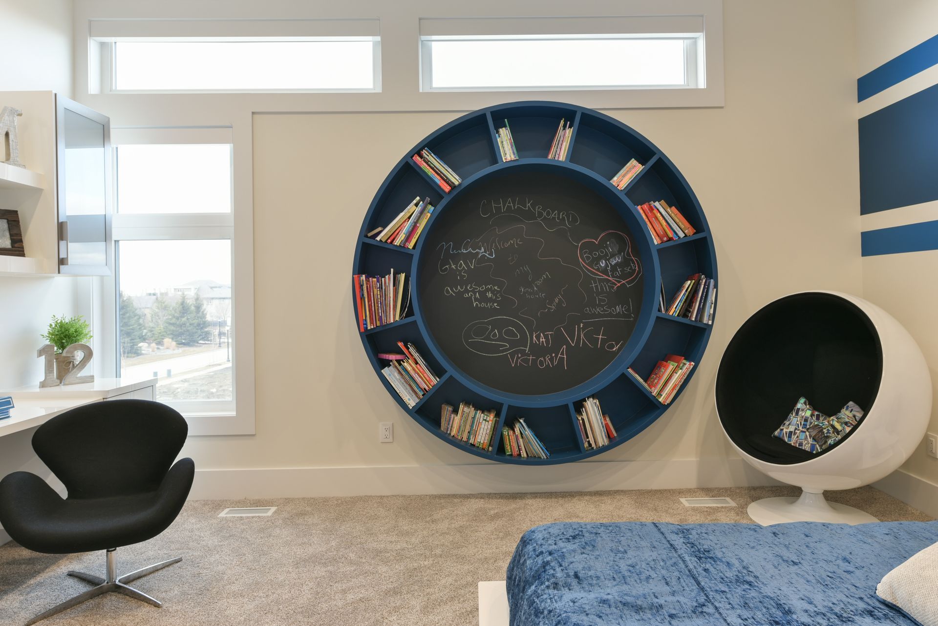 A bedroom with a circular bookshelf and a chalkboard on the wall.