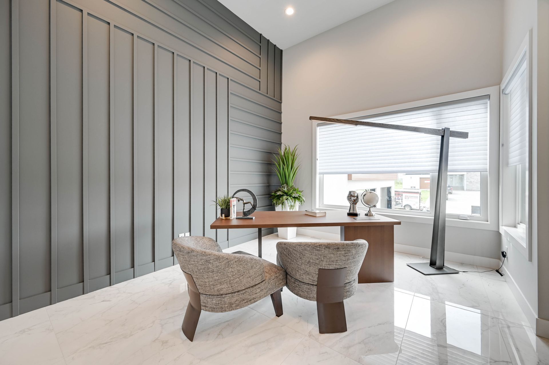 A home office with a desk , chairs and a large window.