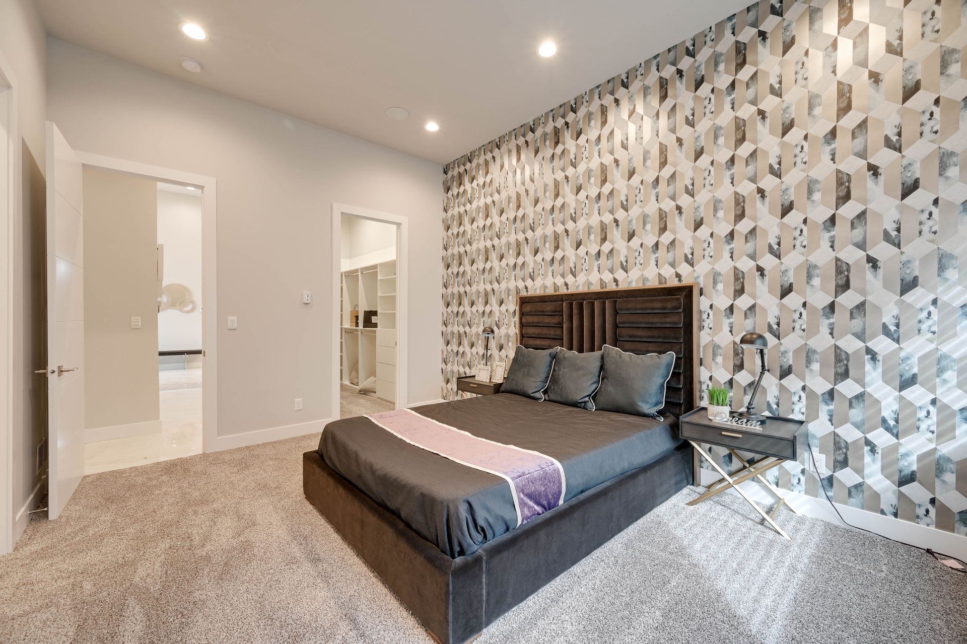 A bedroom with a large bed and a patterned wall.