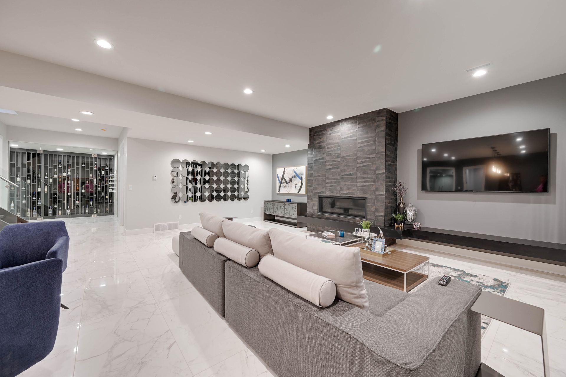 A living room with a couch , chairs , television and fireplace.