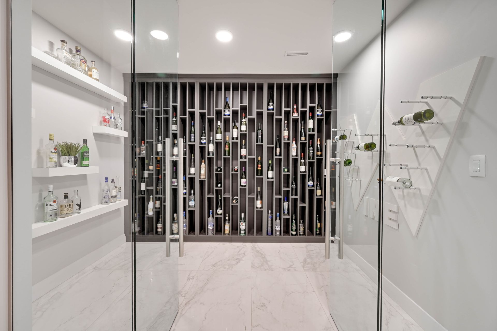 A wine cellar with a glass door and shelves filled with wine bottles.