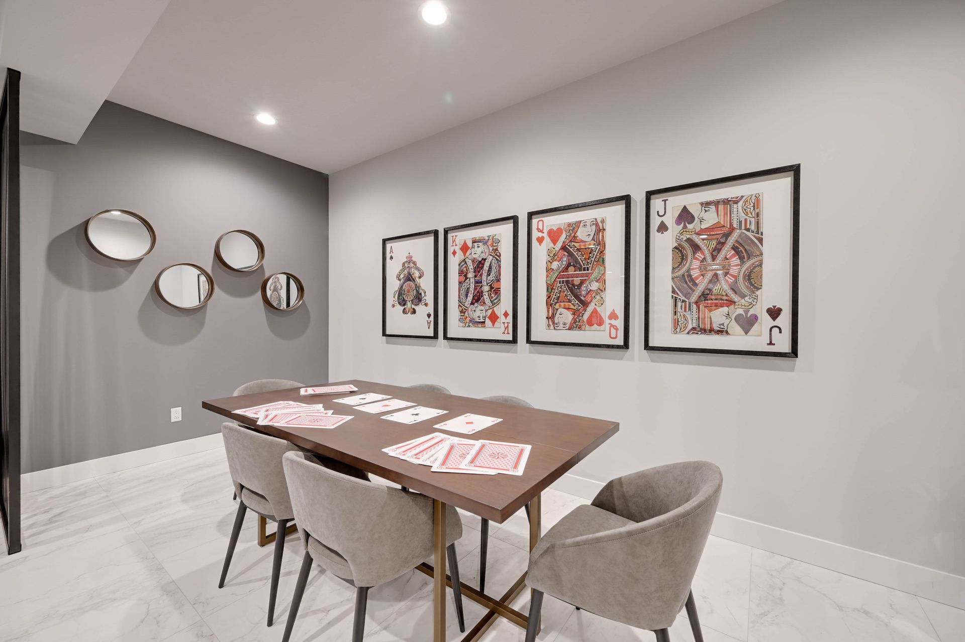 A room with a table and chairs and playing cards on the wall.