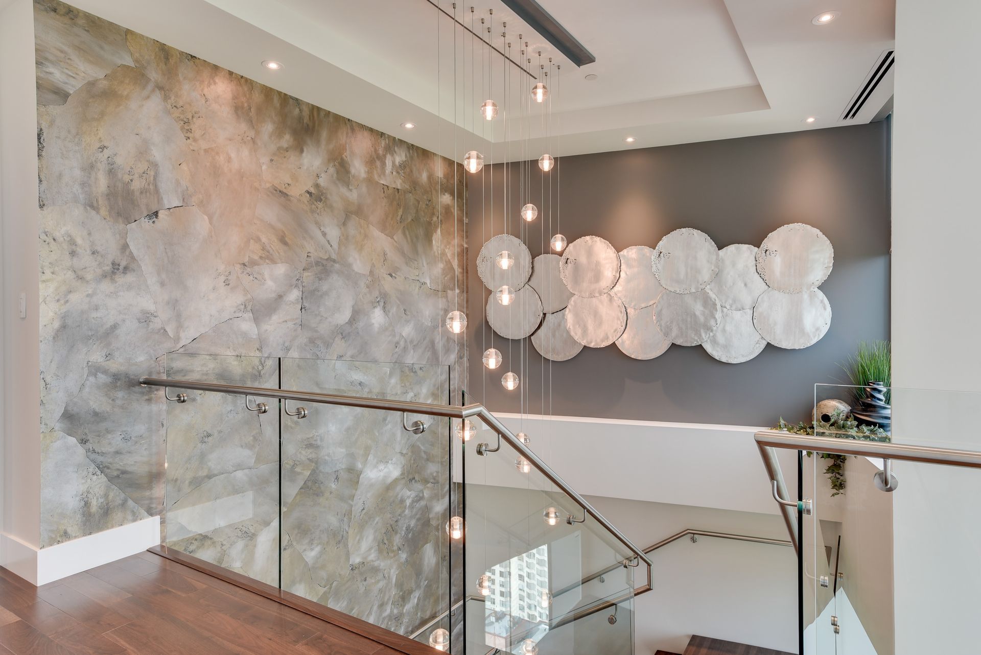 A staircase with a glass railing and a painting on the wall.