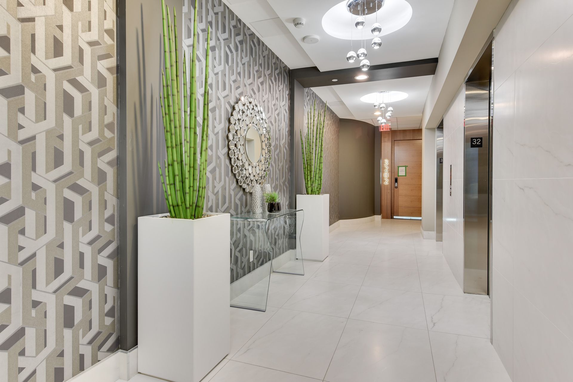 A hallway in a building with elevators and potted plants.