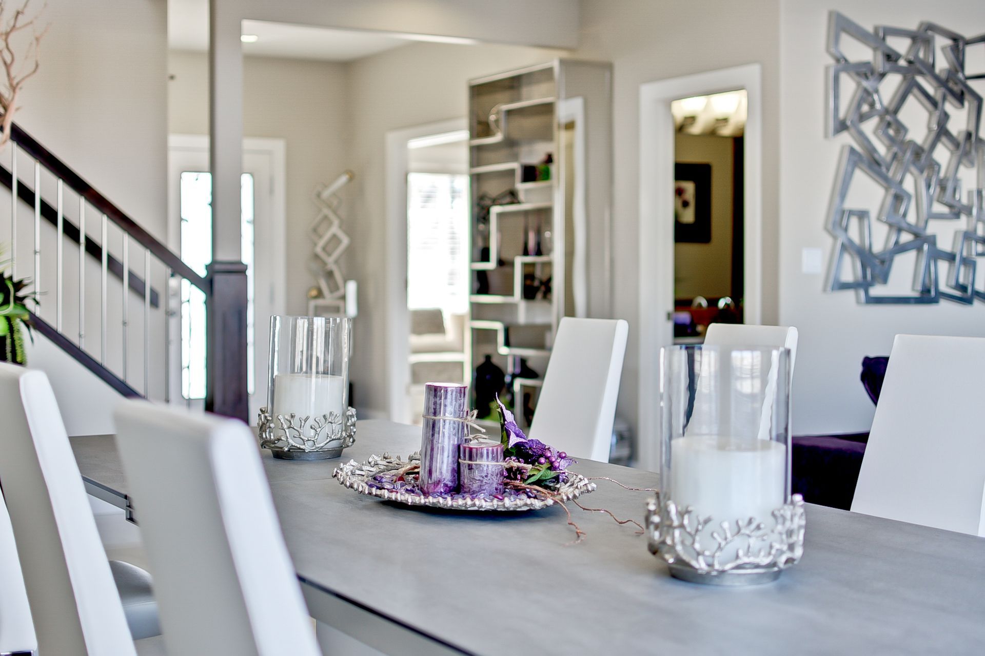 A dining room table with white chairs and candles on it