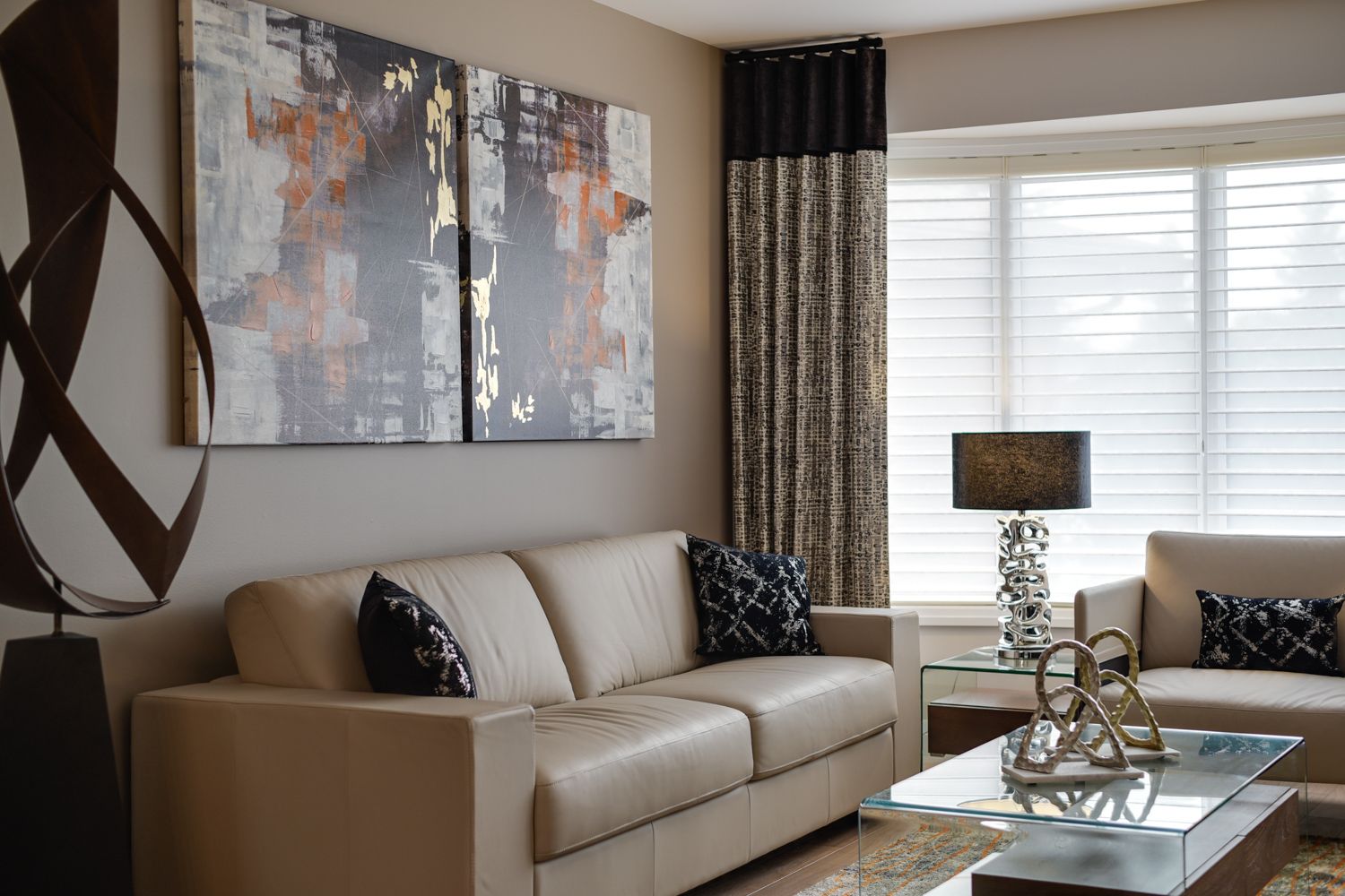 A living room with a couch , two couches , a coffee table and two paintings on the wall.