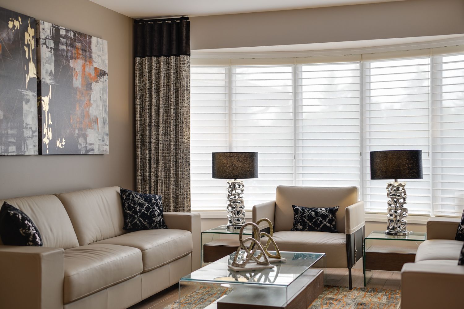 A living room with a couch , chairs , coffee table and lamps.