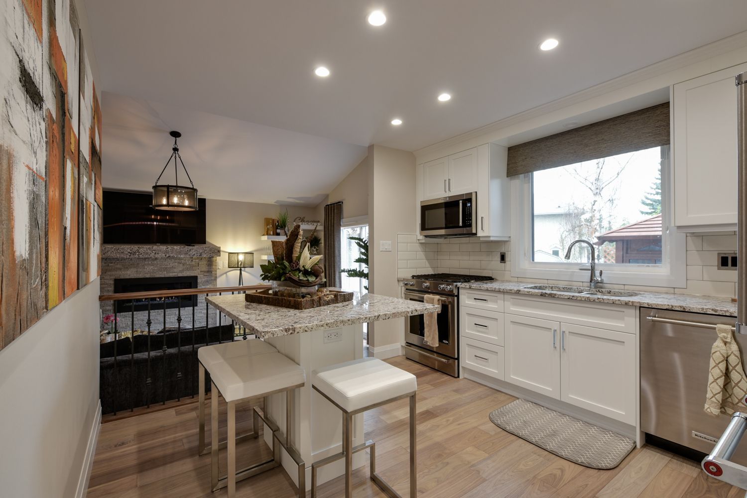 A kitchen with white cabinets , stainless steel appliances and a large island.