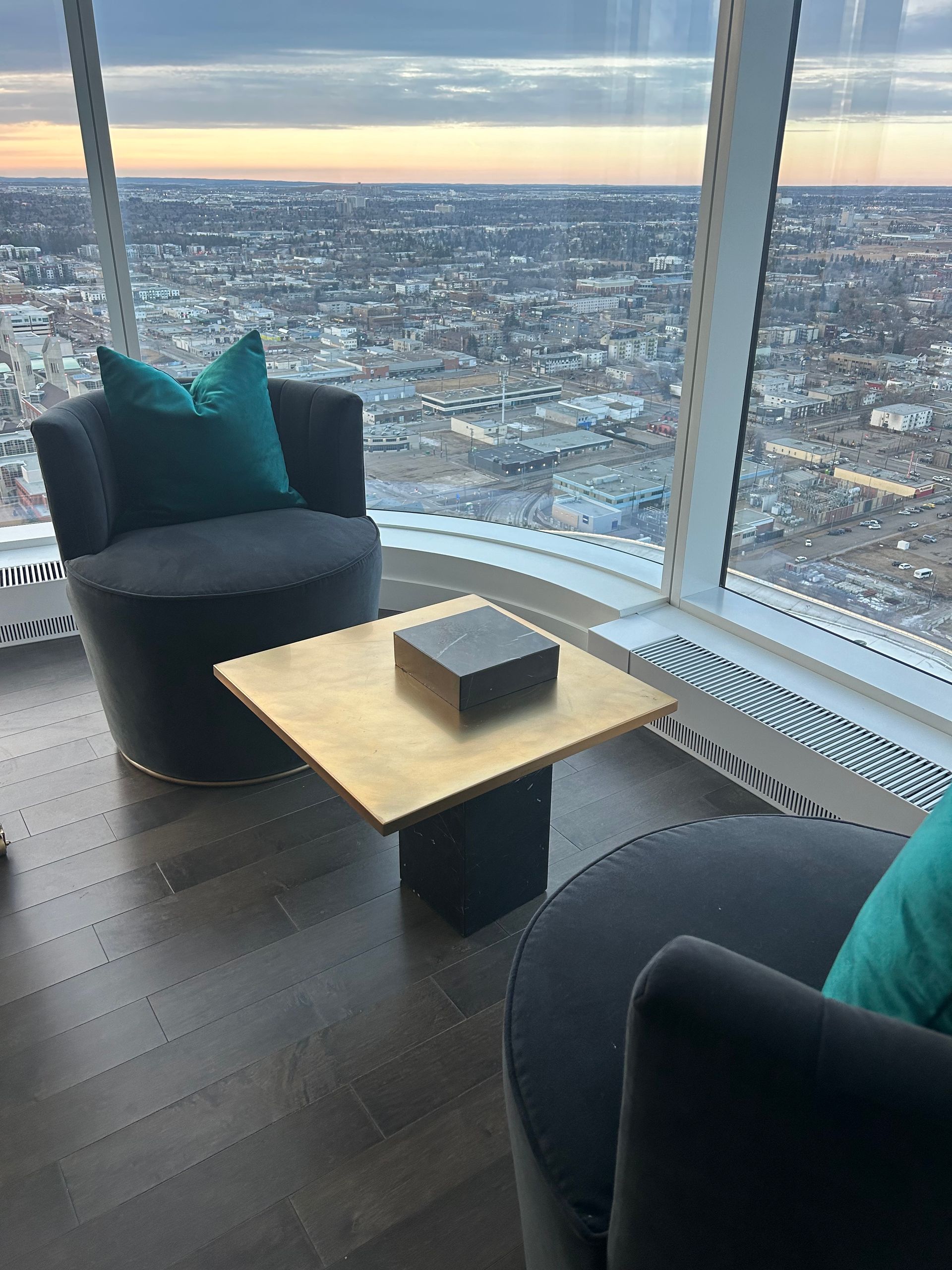 A living room with two chairs and a coffee table with a view of the city.