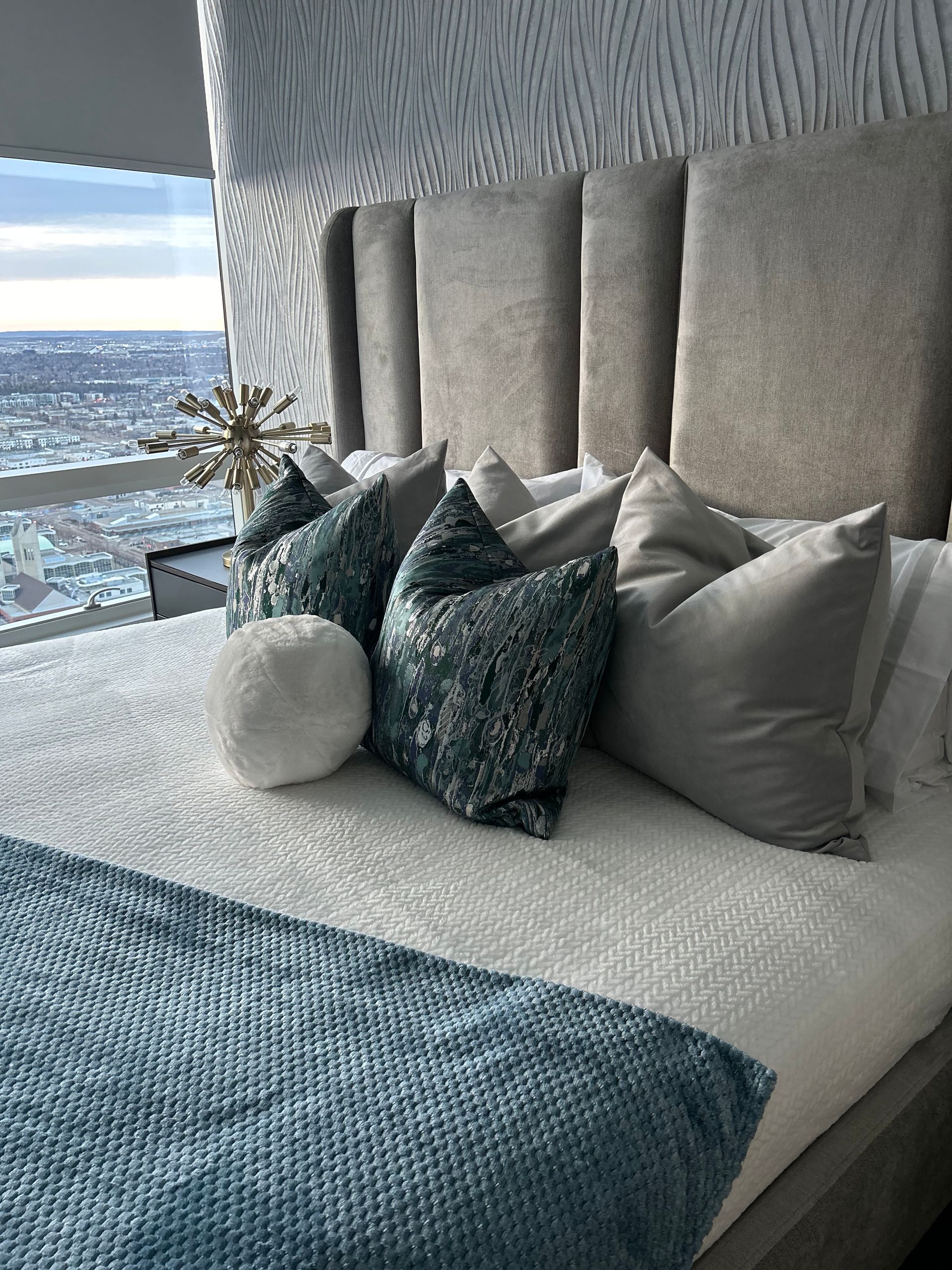 A bed with a headboard and pillows in a bedroom with a view of the city.