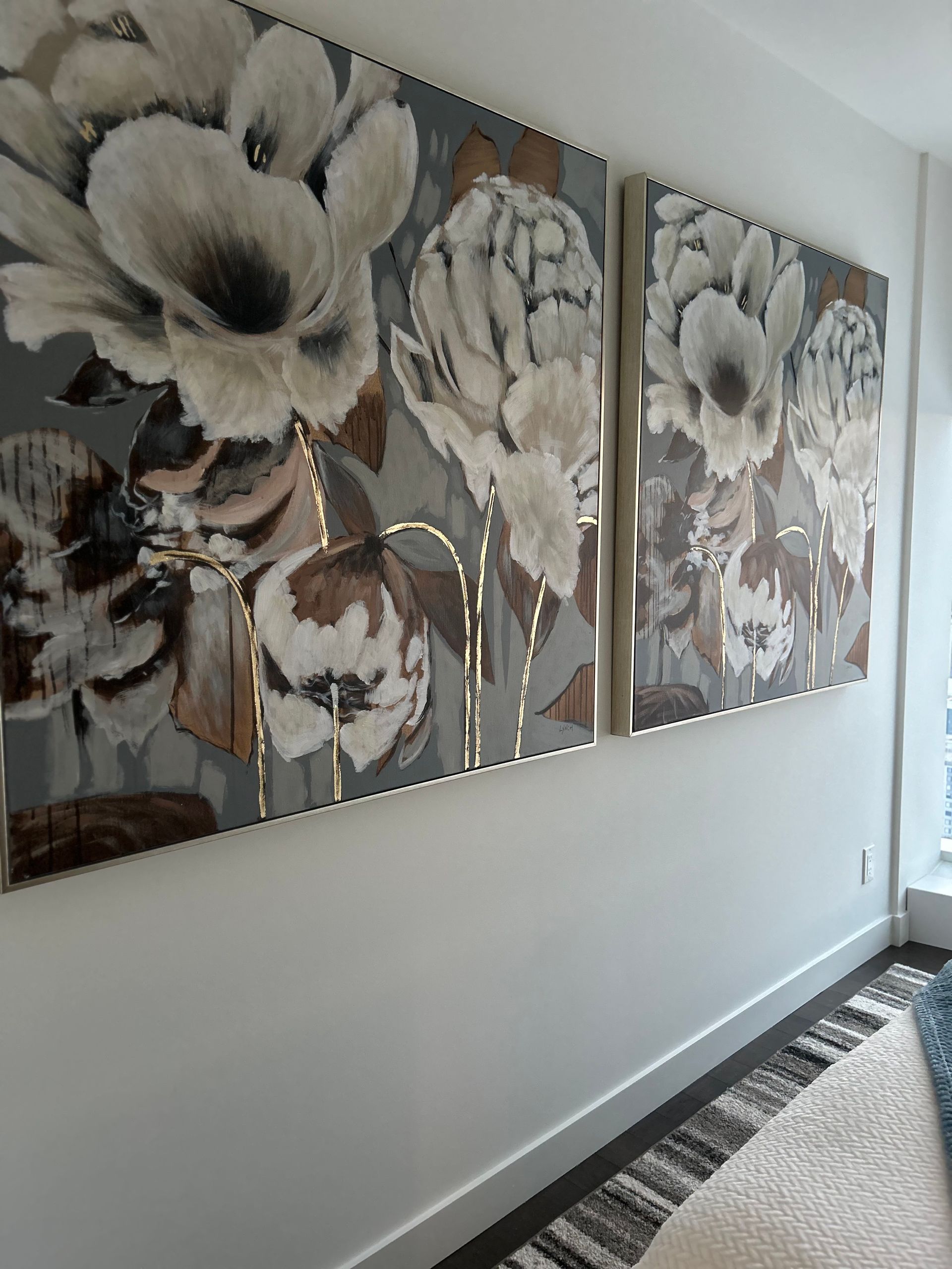 Three paintings of flowers are hanging on a wall in a living room.
