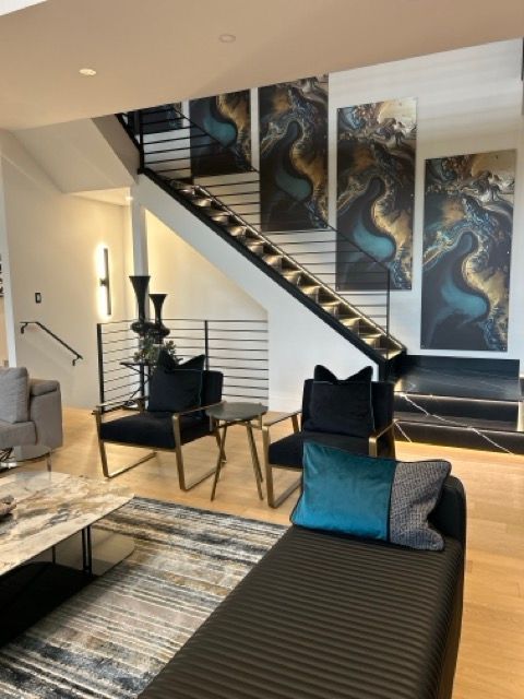 A living room with a couch and chairs and a staircase