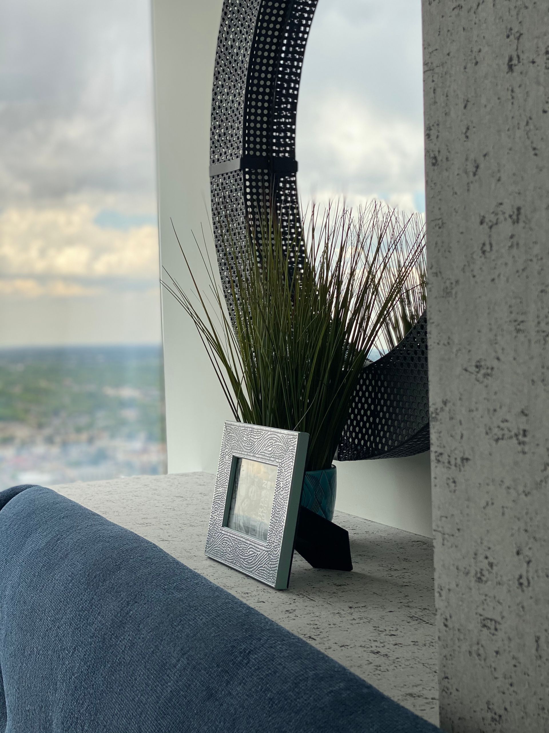 A picture frame sits on a window sill next to a plant