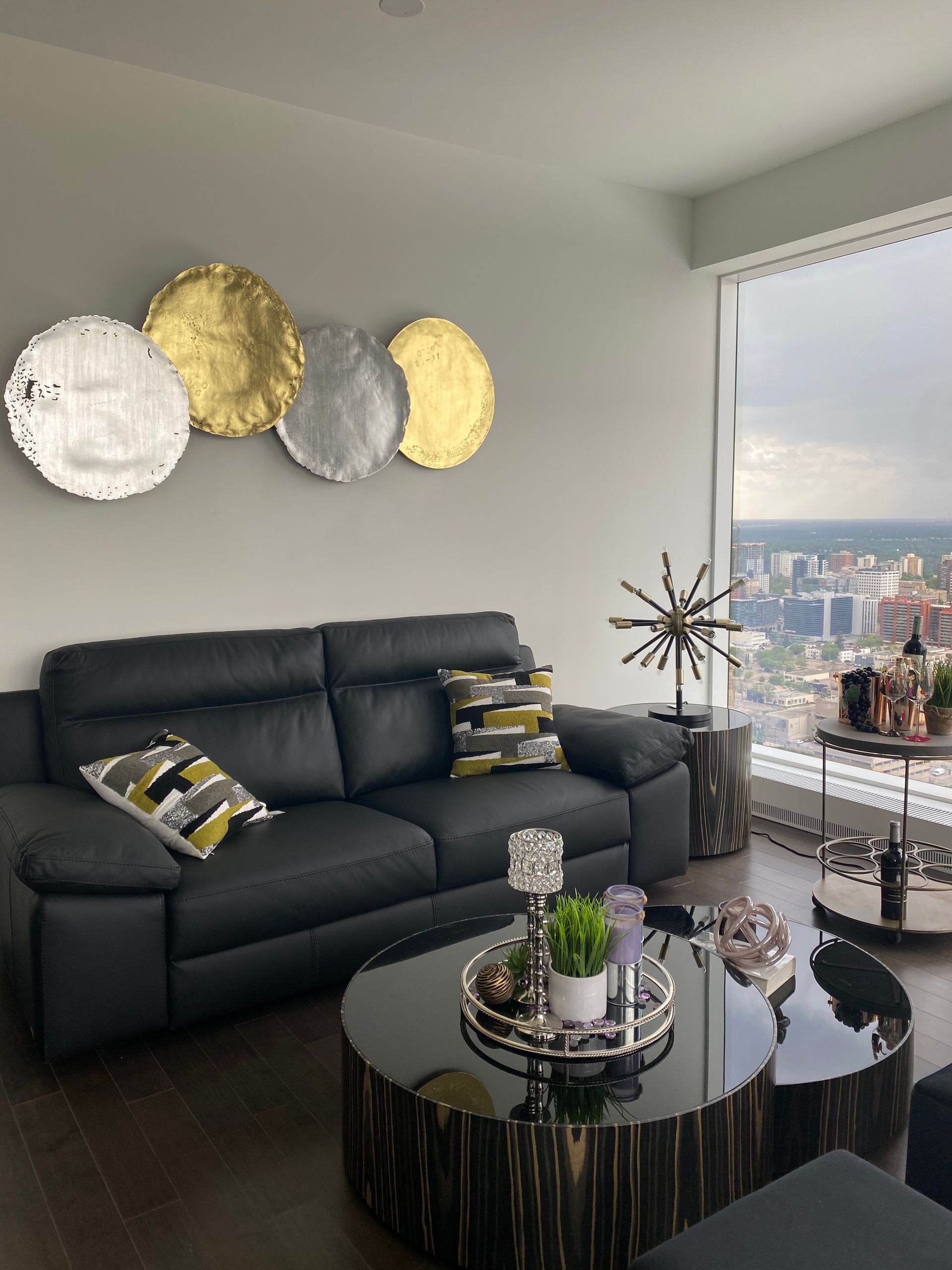 A living room with a black couch and a round coffee table
