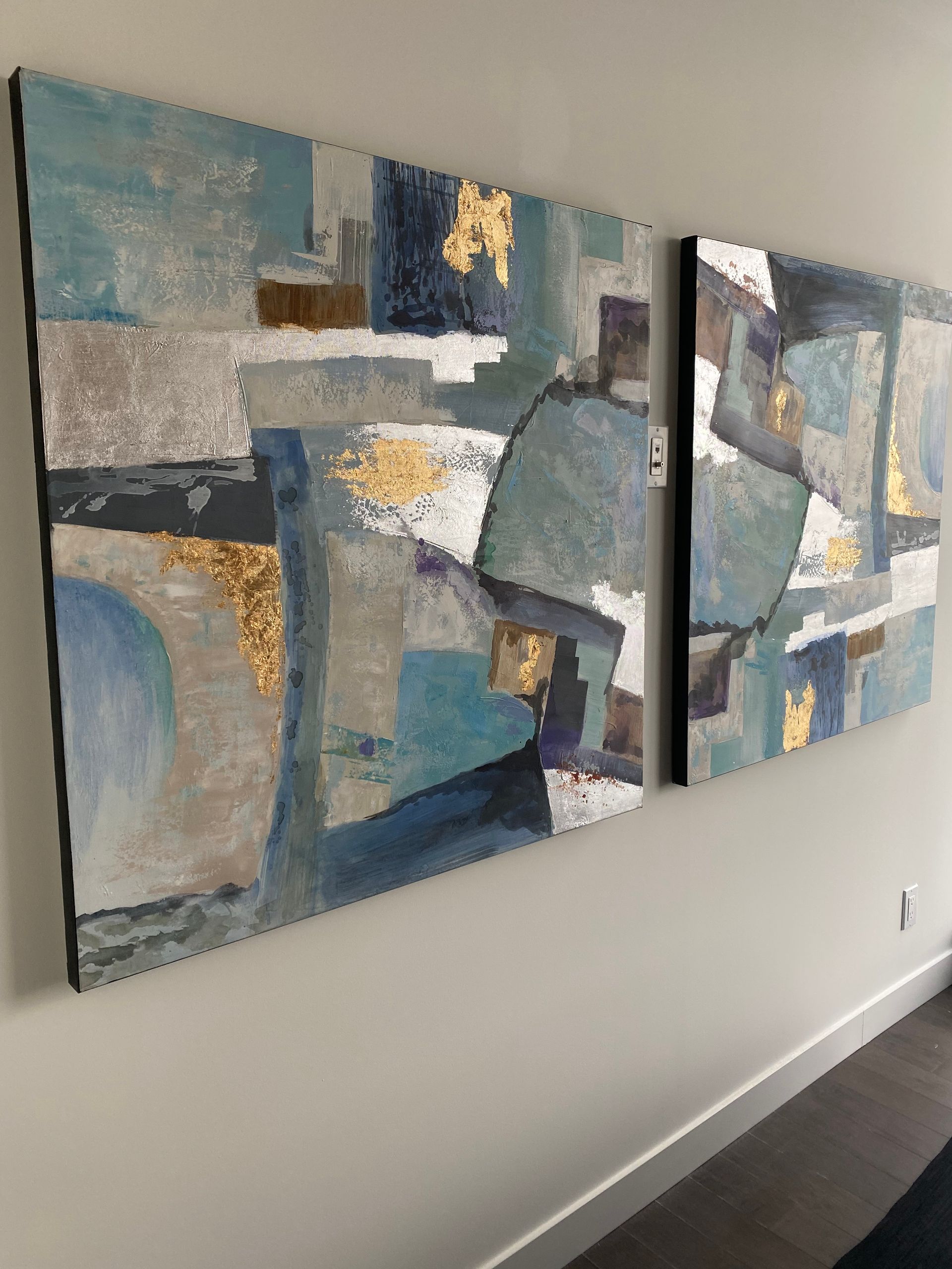 Two paintings are hanging on a wall in a room.